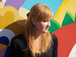 © Yanina - Close up portrait of young ginger woman against colorful mural wall