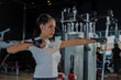 © whyframeshot - fit Asian woman working out at the gym, doing cable machine exercise wearing a gray sports top, showing strength, muscle, and determination in a modern fitness studio.