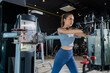 © whyframeshot - fit Asian woman working out at the gym, doing cable machine exercise wearing a gray sports top, showing strength, muscle, and determination in a modern fitness studio.