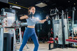 © whyframeshot - fit Asian woman working out at the gym, doing cable machine exercise wearing a gray sports top, showing strength, muscle, and determination in a modern fitness studio.