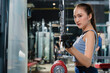 © whyframeshot - fit Asian woman working out at the gym, doing cable machine exercise wearing a gray sports top, showing strength, muscle, and determination in a modern fitness studio.