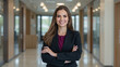 © jesus - Retrato corporativo de mujer en oficina con blazer oscuro y top granate, brazos cruzados, sonrisa y fondo de pasillo