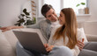 © My Ocean studio - Couple sharing a warm look on the couch while using a laptop, soft foreground blur and cozy home atmosphere.