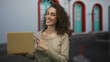 © Krakenimages.com - Woman points finger at cardboard box while holding it by chest near arched doors on a street; happiness delivery business.