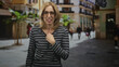 © Krakenimages.com - Woman with glasses touches chest while speaking and later waves on a busy street with shoppers; sincerity greeting.
