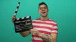 © Krakenimages.com - Man holding clapperboard with smile against isolated green background wearing striped shirt tattoos film concept