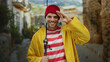 © Krakenimages.com - Hispanic fisherman smiling in urban street while wearing yellow raincoat red striped shirt and beanie holds fishing rod outdoors.