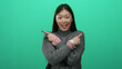 © Krakenimages.com - Woman smiling while pointing in opposite directions against vibrant green backdrop wearing cozy sweater and pink watch highlighting playful expression and modern style