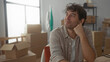 © Krakenimages.com - Hispanic man smiling in new home surrounded by moving boxes, capturing a fresh start and excitement in the cozy modern house.