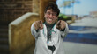 © Krakenimages.com - Handsome hispanic man doctor smiling in a mediterranean town wearing coat stethoscope glasses pointing joyfully against blurred ancient stone backdrop