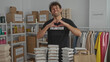 © Krakenimages.com - Man smiling in donation room creating heart with hands surrounded by packaged meals and donation boxes highlighting volunteer work and community support.