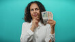 © Krakenimages.com - Woman holding british pound banknotes with thoughtful expression against blue background