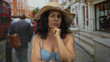 © Krakenimages.com - Woman in bikini with thinking pose and straw hat stands on urban street resembling london, surrounded by red buses and historical architecture.