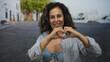 © Krakenimages.com - Hispanic woman smiling in bikini and shirt outdoors on sunny street showing love with hands.