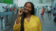 © Krakenimages.com - Woman with curly hair in yellow shirt making small gesture at airport terminal.