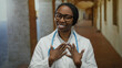 © Krakenimages.com - Woman doctor standing confidently in a historical university hallway with stethoscope around neck while smiling, exhibiting pride and assurance in her academic environment.
