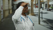 © Krakenimages.com - Female doctor in white coat with stethoscope searching under daylight in an urban street wearing glasses and looking focused.