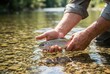 © Stitch - Person catching a fish with both hands in a clear stream during daytime near trees and stones
