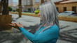 © Krakenimages.com - Woman with grey hair in blue shirt gestures with hands outdoors on street background