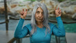 © Krakenimages.com - Woman expressing joy at seaside outdoor with peace gestures, grey hair gently flowing in beach breeze, capturing serene and relaxed senior vibe in natural setting.