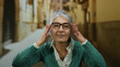 © Krakenimages.com - Elderly woman with grey hair and glasses adjusts her hair while standing confidently on an outdoor street, showcasing a serene and thoughtful expression in the urban environment.