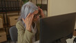 © Krakenimages.com - Woman with grey hair looking stressed at a computer in an office, showing workplace frustration and senior professional challenges in an indoor setting.