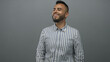 © Krakenimages.com - Man smiling with beard in gray studio, wearing a blue striped shirt and looking to the side with relaxed posture; happiness.