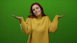 © Krakenimages.com - Woman redhead wearing yellow sweater stands against vibrant green wall showcasing a thoughtful expression with closed eyes while gesturing with her hands in a peaceful manner.