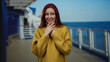© Krakenimages.com - Young woman with red hair on a boat at sea wearing a yellow sweater, displaying emotion in a scenic seaside setting with a clear sky in the outdoor background.