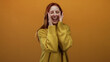 © Krakenimages.com - Woman shouting with eyes closed in front of an orange background wearing a cozy sweater, conveying excitement or surprise, redhead featuring joy and emotion, emphasizing female presence.