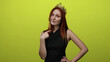 © Krakenimages.com - Woman with red hair wearing a crown points confidently to herself against a vivid yellow background, embodying self-assured beauty and poise.
