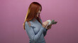 © Krakenimages.com - Woman holding swedish banknotes smiles against an isolated pink background, showcasing currency and financial concepts with a focus on her red hair and beautiful expression.