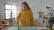 © Krakenimages.com - Woman ironing in a cozy laundry room wearing headphones and a yellow sweater, showcasing modern home lifestyle and relaxation.