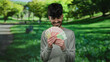 © Krakenimages.com - Man smiling while holding norwegian krone banknotes in a lush green park setting, showcasing happiness and financial success outdoors in norway.