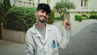 © Krakenimages.com - Man smiling outdoors in city street wearing white lab coat gesturing with hand, showcasing happiness and confidence in urban environment.