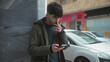 © Krakenimages.com - Young man outdoors in urban setting smoking and using smartphone on city street by parked cars in winter attire expressing modern city lifestyle and technology interaction.