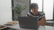 © Krakenimages.com - Teen boy typing on laptop at desk in building, fingers on keyboard and smiling while notebooks and phone nearby; concentration success.