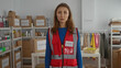 © Krakenimages.com - Woman volunteer in red vest oversees donation center filled with boxes and supplies, showcasing charity work environment.