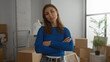 © Krakenimages.com - Woman indoors crossing arms in new apartment surrounded by moving boxes and plants wearing blue sweater.