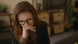 © Krakenimages.com - Woman thinking in an office environment while looking at a computer, surrounded by bookshelves and plants, depicting a focused business setting.