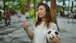 © Krakenimages.com - Young woman holding soccer ball pointing in lively urban street surrounded by people and palm trees on sunny day