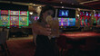 © Krakenimages.com - Woman holding cocktail glass, sipping through a straw and smiling, bare shoulders visible in casino; celebration night out.