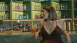 © Krakenimages.com - Woman leaning on bar counter with cocktail, smiling and showing cleavage while seated at the bartop; carefree social joy.