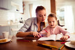 © Davor - Mother helping daughter with homework at kitchen table