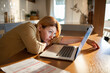 © Davor - Tired woman with burnout working on laptop at home kitchen table