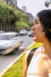© Guillermo Spelucin - Young woman contemplating urban coastal road with motion blur