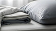 © Zobia - Close up of Neatly Folded Cotton Bed Sheets and Pillow on a Bed with Soft Morning Sunlight