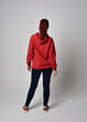 © faestock - full length figure of female model wearing  basic contemporary casual clothing, red hoodie jumper, skinny jeans, sneakers. standing pose walking away back view,  isolated white studio background.