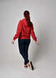 © faestock - full length figure of female model wearing  basic contemporary casual clothing, red hoodie jumper, skinny jeans, sneakers. standing pose walking away back view,  isolated white studio background.