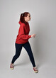 © faestock - full length figure of female model wearing  basic contemporary casual clothing, red hoodie jumper, skinny jeans, sneakers. walking action pose, isolated white studio background.